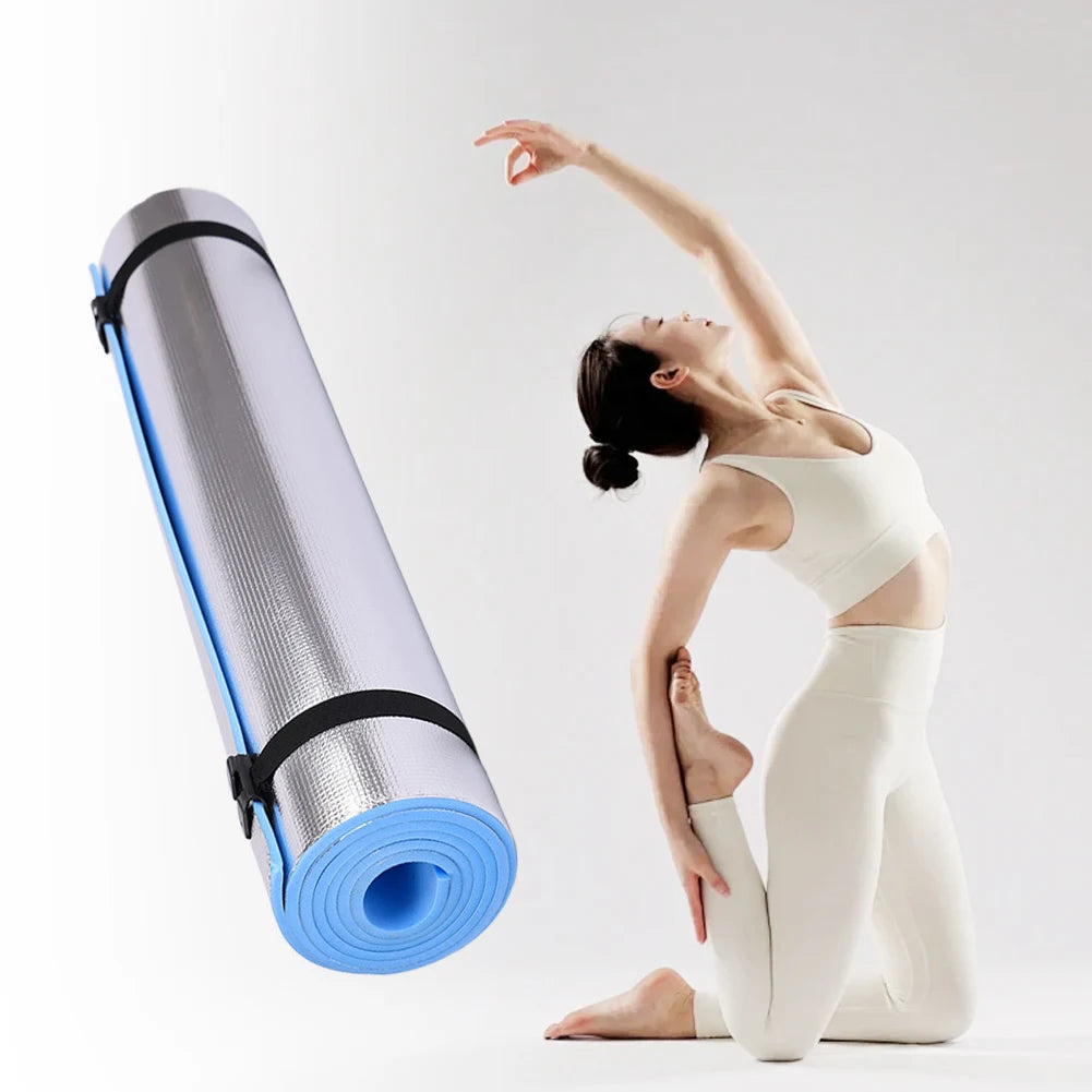 Yoga mat with blue edge and black strap next to a person in a yoga pose on a white background