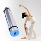 Yoga mat with blue edge and black strap next to a person in a yoga pose on a white background