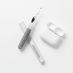 Earbud cleaning pen disassembled next to AirPods case flat lay